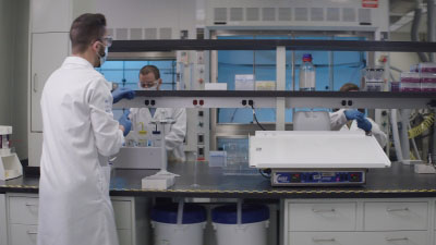 man in lab coat standing at bench
